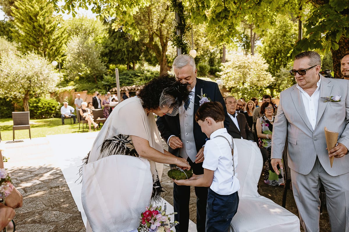 Fotografo matrimonio in Monferrato. Matrimonio di Serena e Fabrizio al Vecchio Castagno di Cocconato d'Asti. Cerimonia. Sposa prende l'anello dal cuscino portato dal nipotino.