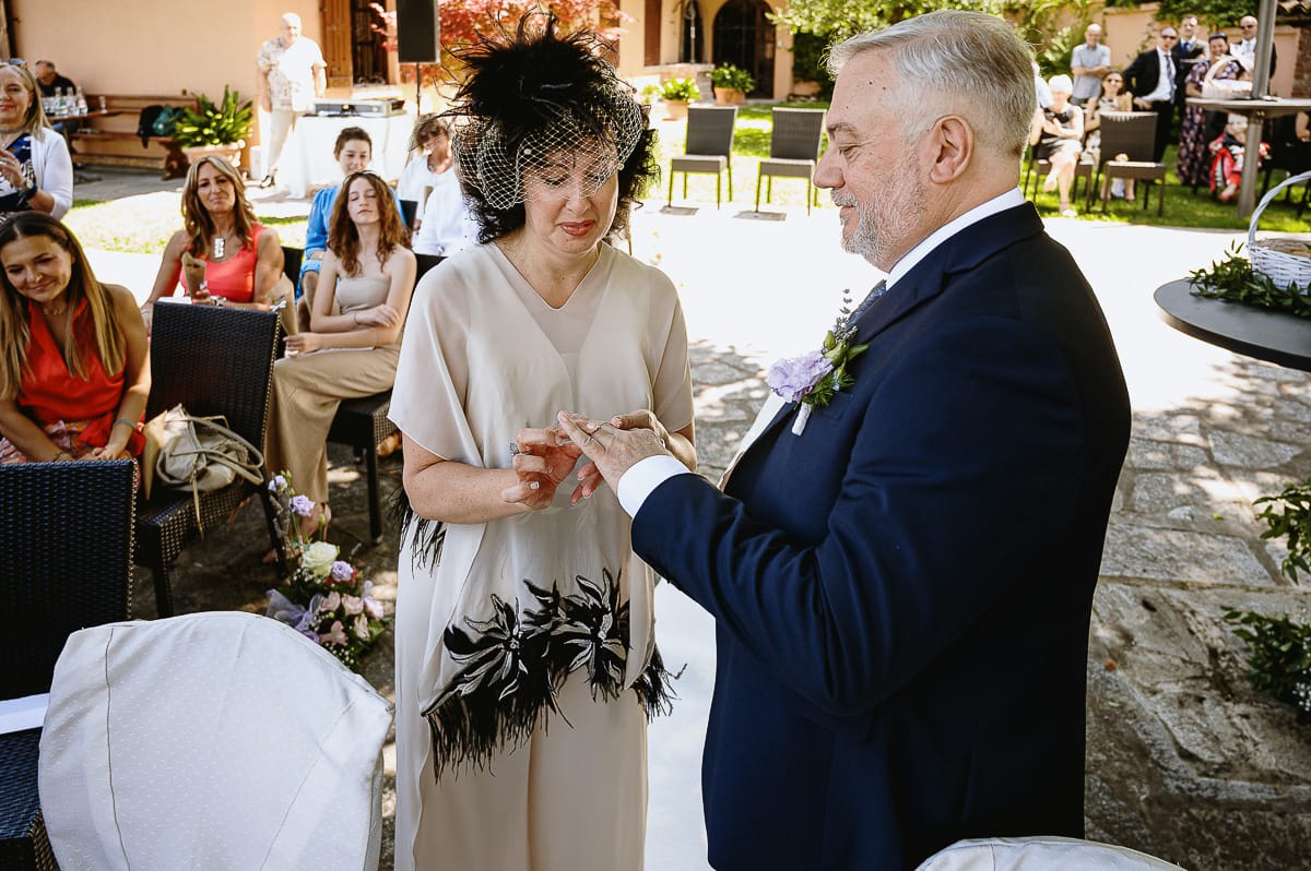 Fotografo matrimonio in Monferrato. Matrimonio di Serena e Fabrizio al Vecchio Castagno di Cocconato d'Asti. Cerimonia. Sposa infila l'anello allo sposo.