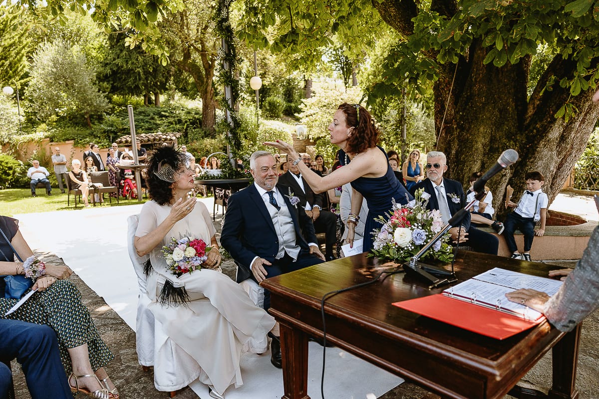 Fotografo matrimonio in Monferrato. Matrimonio di Serena e Fabrizio al Vecchio Castagno di Cocconato d'Asti. Cerimonia. Sorella manda un bacio alla sposa.