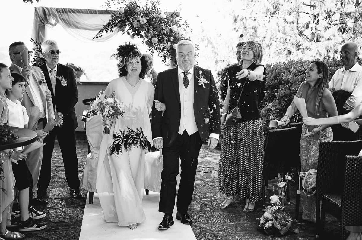 Fotografo matrimonio in Monferrato. Matrimonio di Serena e Fabrizio al Vecchio Castagno di Cocconato d'Asti. Cerimonia. Uscita degli sposi con lancio dei petali. Bianco enero.