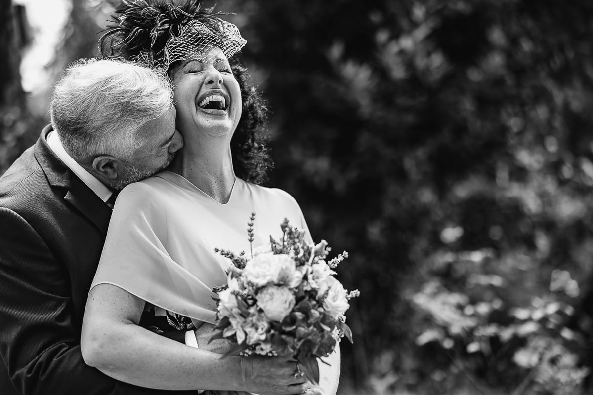Fotografo matrimonio in Monferrato. Matrimonio di Serena e Fabrizio al Vecchio Castagno di Cocconato d'Asti. Ritratti di coppia degli sposi. Bel ritratto in bianco e nero sorridente degli sposi. Spoo bacia la sposa sul collo.