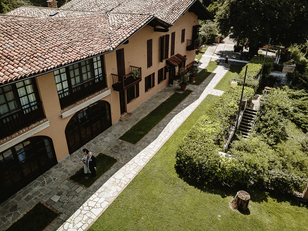 Fotografo matrimonio in Monferrato. Matrimonio di Serena e Fabrizio al Vecchio Castagno di Cocconato d'Asti. Ritratti di coppia degli sposi. Sposi camminano verso la zona dell'aperitivo. Foto aerea dal drone.