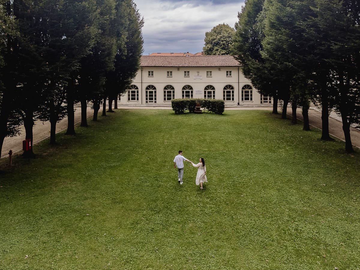 Pre-wedding al Castello di Santena. Fabiola e Cristian camminano sul prato tenendosi per mano. Foto dal drone