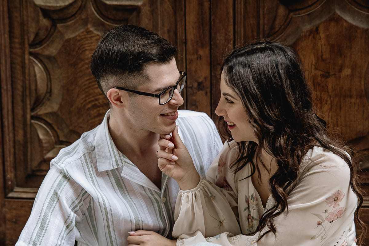 Pre-wedding al Castello di Santena. Fabiola e Cristian seduti davanti ad un portone si guardano teneramente.