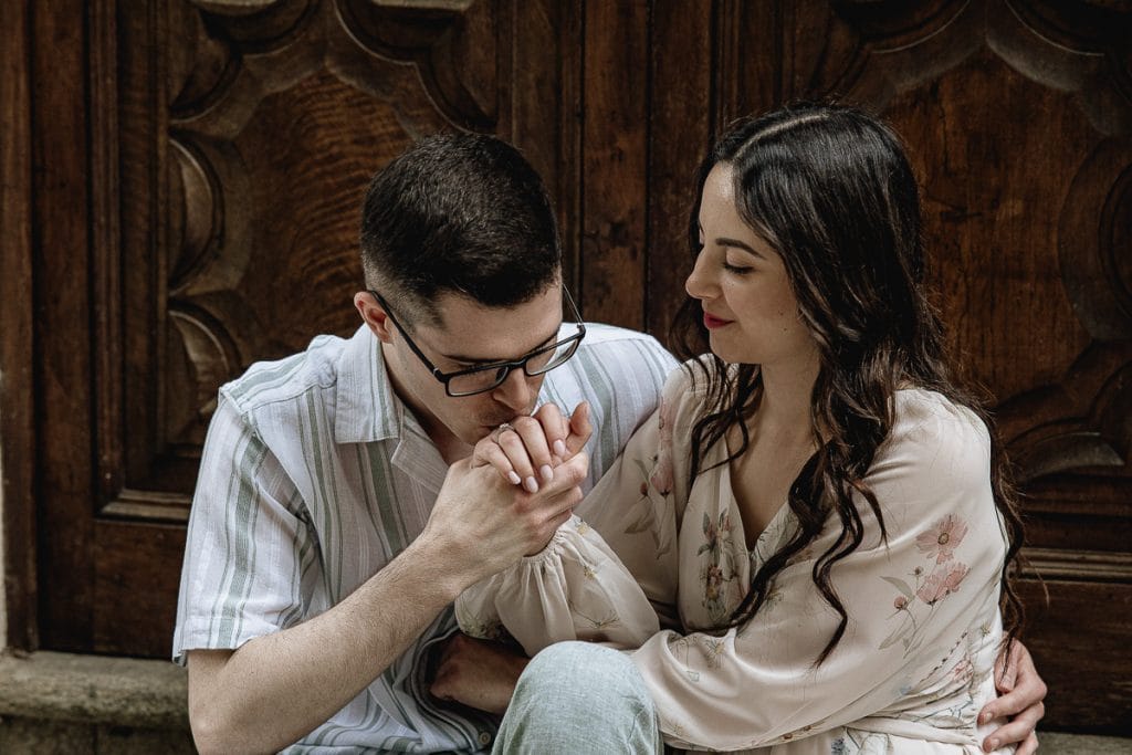 A magical pre-wedding at Castello di Santena. Fabiola and Cristian share a tender moment, seated before a grand doorway, as he gently kisses her hand.  