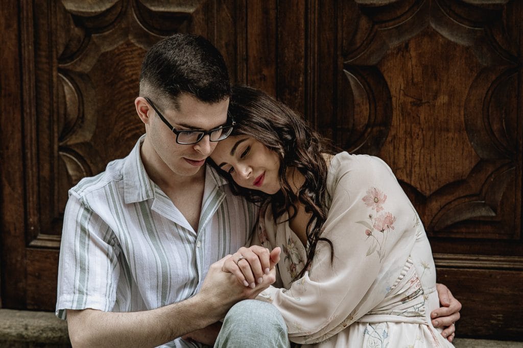 A magical pre-wedding at Castello di Santena. Fabiola and Cristian share a tender moment, seated before a grand doorway, their arms entwined. 