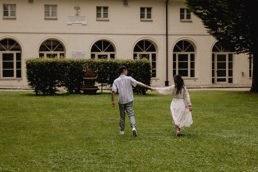 Pre-wedding at Castello di Santena. Fabiola and Cristian walk hand in hand across the lawn. 