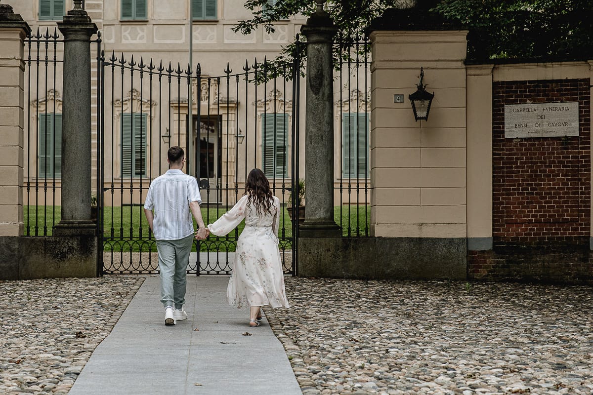 Pre-wedding al Castello di Santena. Fabiola e Cristian camminano dandosi la mano verso il cancello del castello