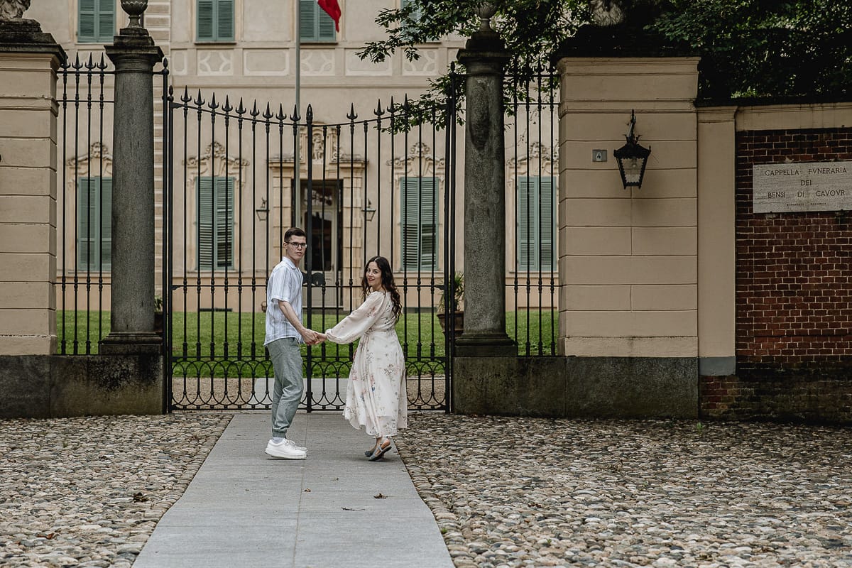 Pre-wedding al Castello di Santena. Fabiola e Cristian camminano dandosi la mano verso il cancello del castello voltandosi indietro