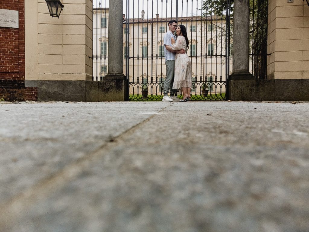Pre-wedding at Castello di Santena. Fabiola and Cristian embrace in front of the castle gate. Photo taken from a drone on the pavement.  