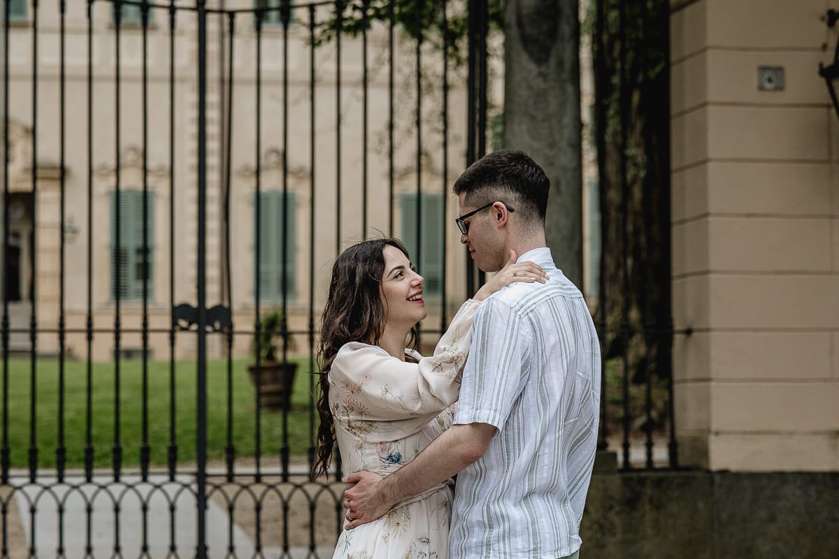 Pre-wedding al Castello di Santena. Fabiola e Cristian davanti al cancello del castellosi guardano sorridendo.