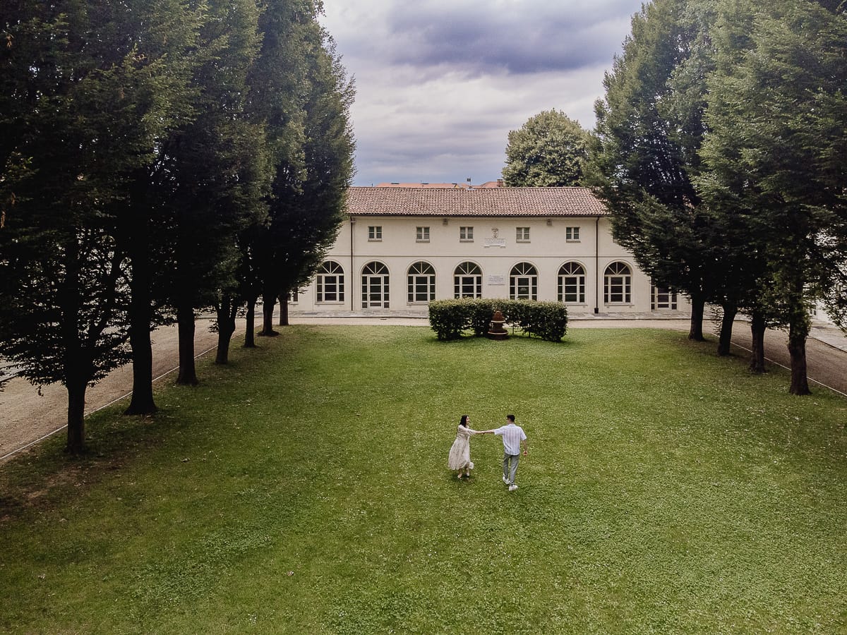 Pre-wedding al Castello di Santena. Fabiola e Cristian camminano sul prato tenendosi per mano. Foto aerea dal drone.