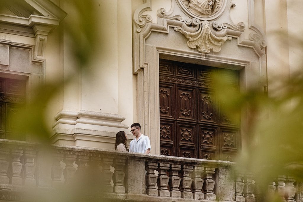 Fabiola and Cristian pose on the church steps during their pre-wedding at Castello di Santena. Photo taken through foliage.  