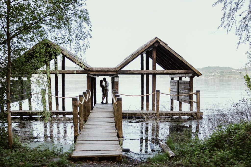 Ilaria and Luca's enchanting pre-wedding shoot at Lake Viverone. Silhouettes of the couple against the backdrop of prehistoric pile dwellings. 
