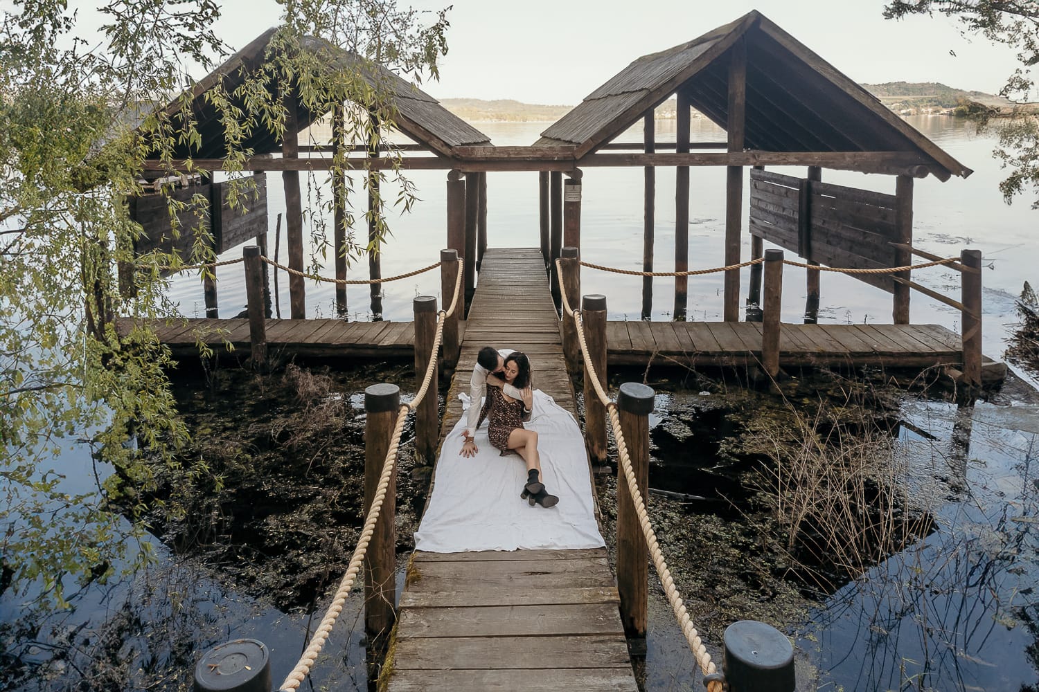 Pre-wedding al Lago di Viverone di Ilaria e Luca. Foto aerea dal drone della coppia seduta sul pontile del Lago