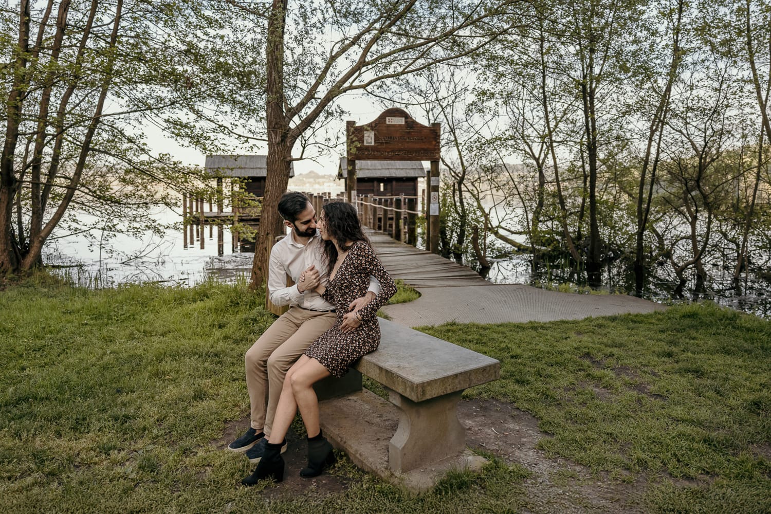 Pre-wedding al Lago di Viverone di Ilaria e Luca. Foto della coppia seduta su di una panchina in pietra davanti alla zona delle palafitte.