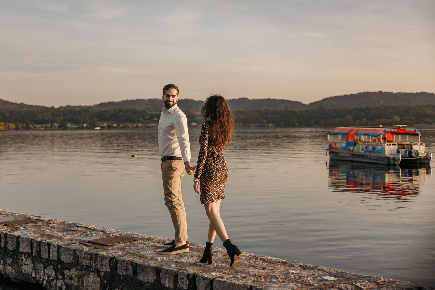 Pre-wedding al Lago di Viverone di Ilaria e Luca. La coppia passeggia sul pontile di pietra sul lago.