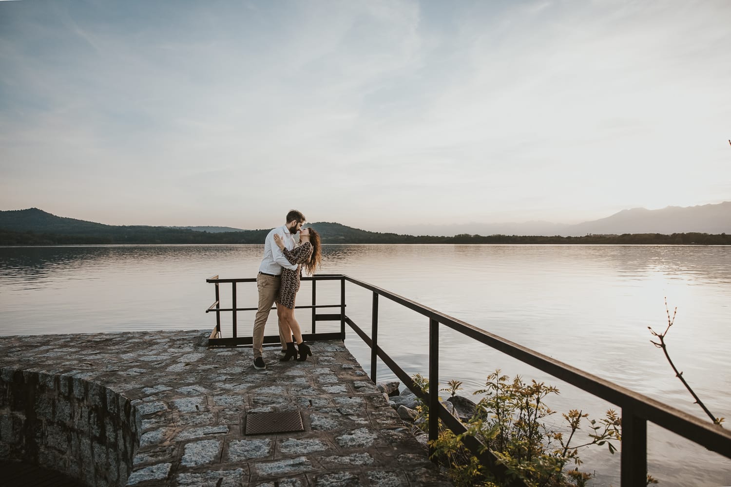 Pre-wedding al Lago di Viverone di Ilaria e Luca. Coppia fa un casquet sul pontile di pietra sul lago.
