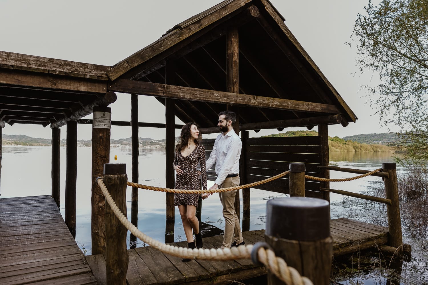 Pre-wedding al Lago di Viverone di Ilaria e Luca. Ilaria tira Luca camminando sul pontile delle palafitte.