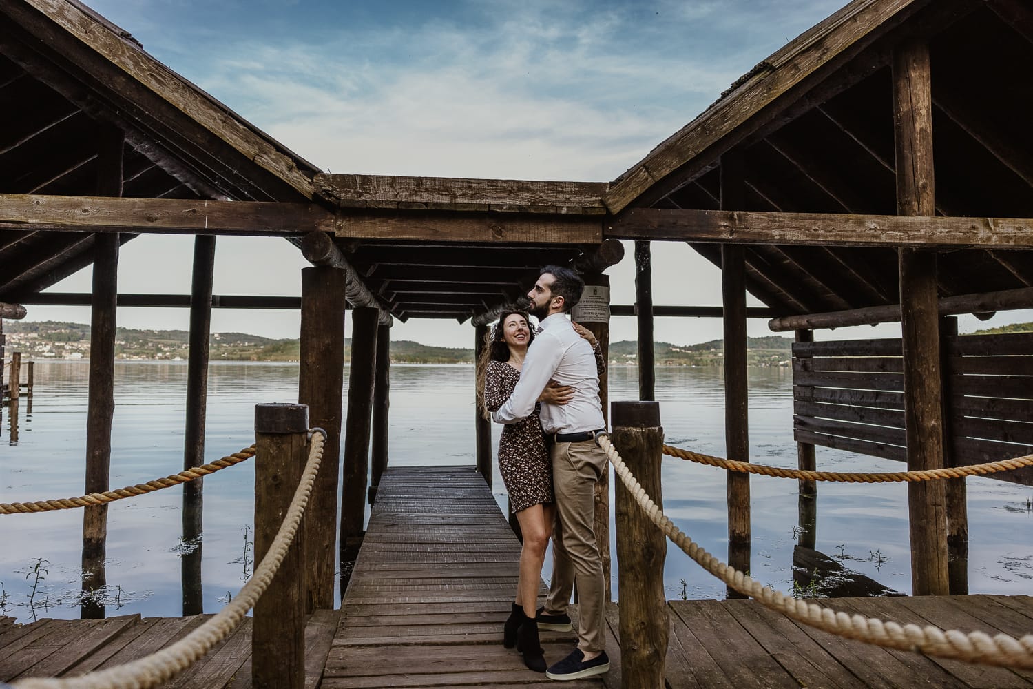 Pre-wedding al Lago di Viverone di Ilaria e Luca. La coppia si abbraccia sul pontile delle palafitte.