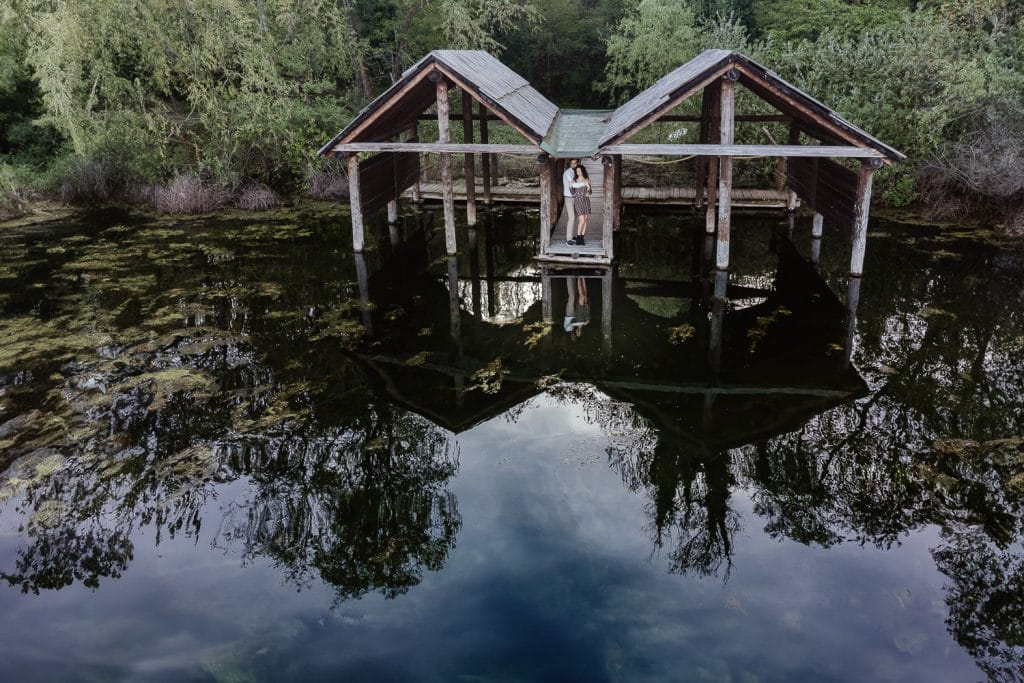 A stunning aerial drone shot captures Ilaria and Luca during their pre-wedding photoshoot at Lake Viverone. The couple, standing among the ancient pile dwellings, is beautifully reflected in the tranquil waters.  