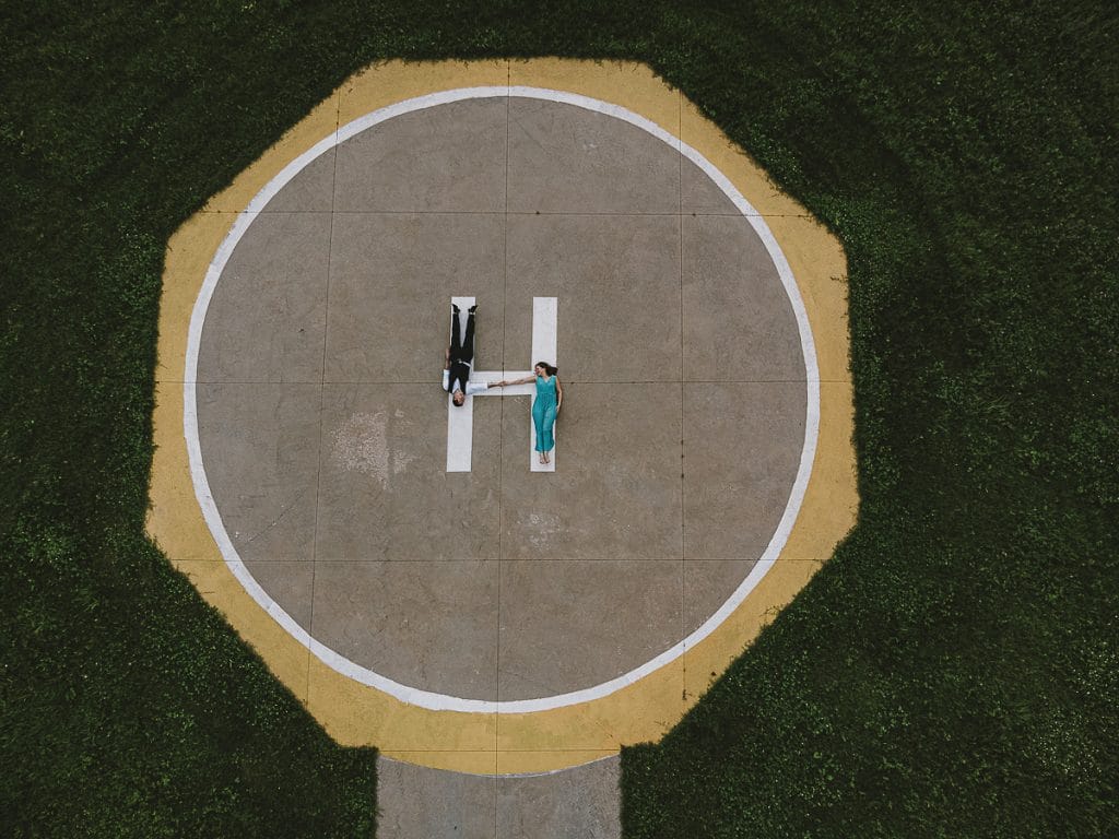 卡斯特尔努沃·顿·博斯科航空俱乐部的婚前拍摄。维多利亚和克里斯蒂安躺在直升机着陆跑道上的空中照片，背景是绿草如茵的草地。  