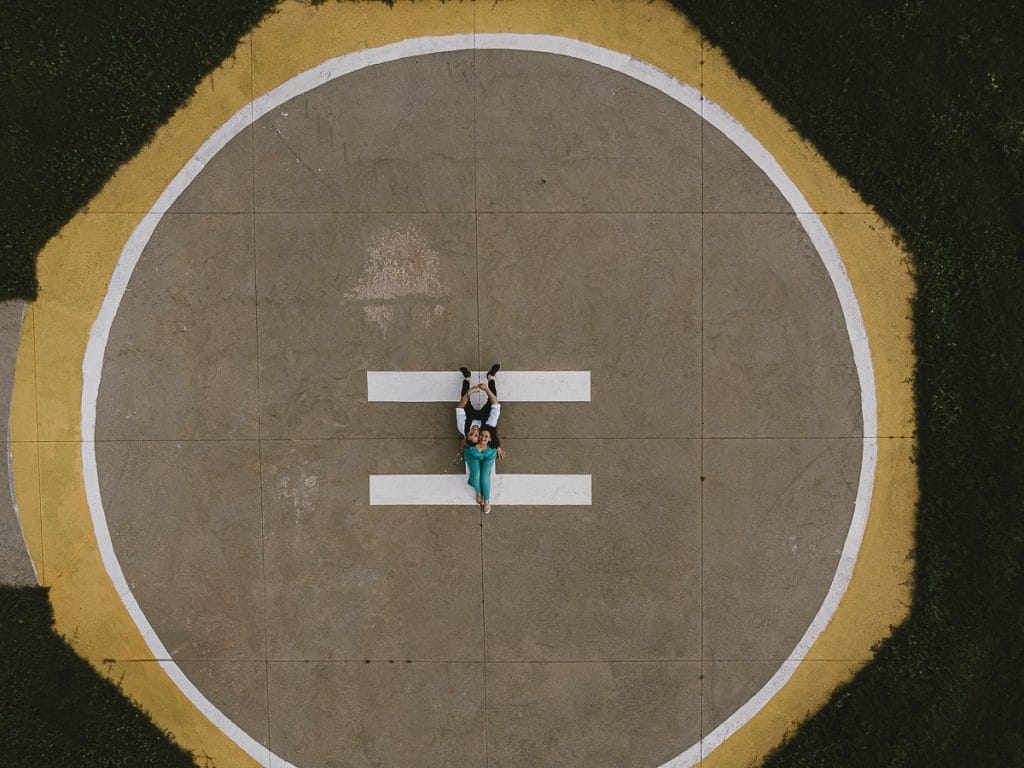 卡斯特尔努沃·顿·博斯科航空俱乐部的婚前拍摄。维多利亚和克里斯蒂安躺在直升机着陆跑道上的空中照片，背景是绿草如茵的草地。  