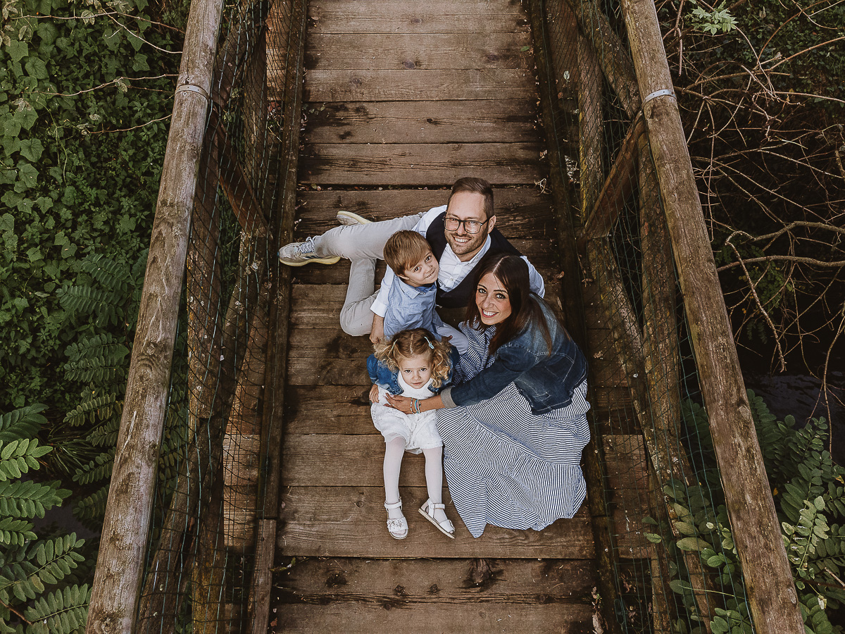 Fotografia di famiglia a Chieri, nel Giardino del Tessile. La famiglia è seduta sul ponte di legno sopra il Rio Tepice. Foto aerea dal drone.