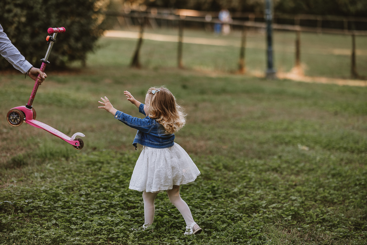 Fotografia di famiglia a Chieri, nel Giardino del Tessile. Camilla che corre verso il papà per prendere il monopattino rosa.