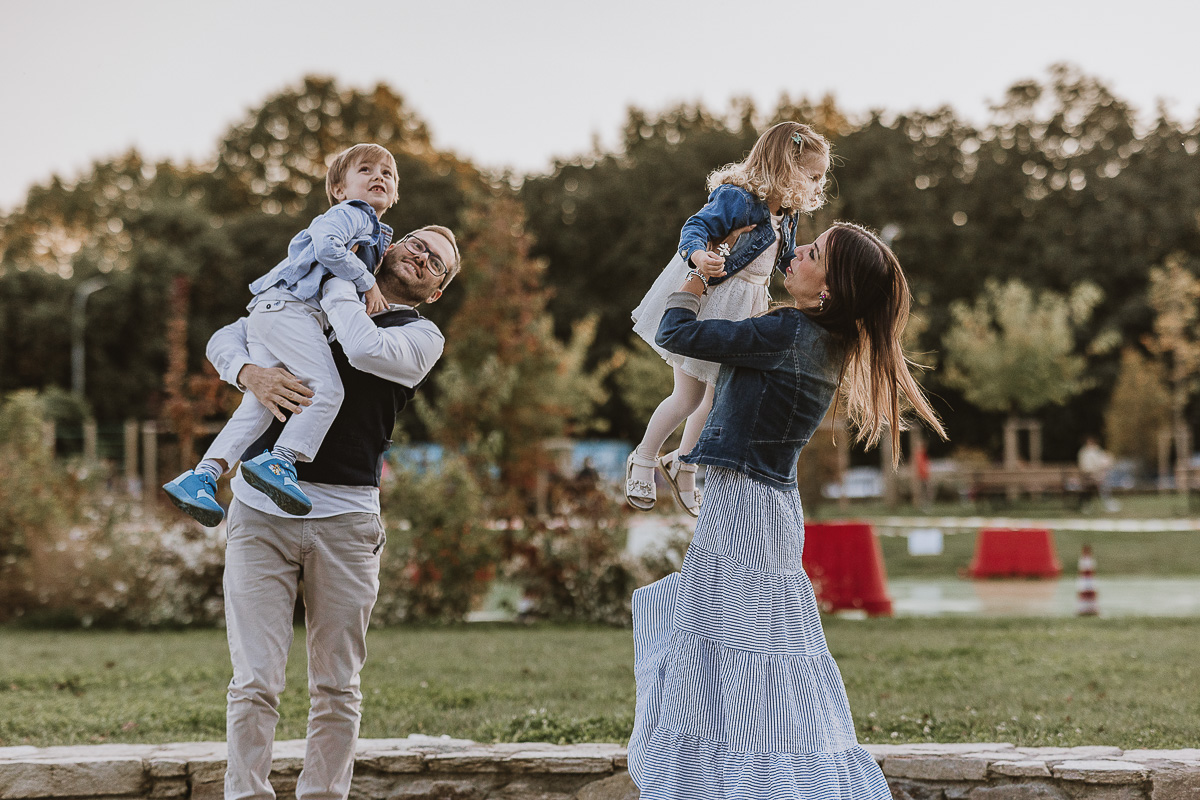 Fotografia di famiglia a Chieri, nel Giardino del Tessile. I genitori prendono in braccio i bambini.