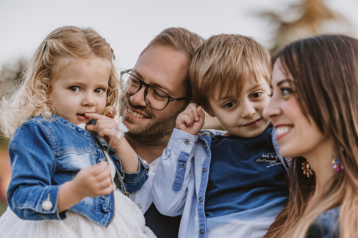 Fotografia di famiglia a Chieri, nel Giardino del Tessile. I genitori hanno i bambini in braccio. Cami ha un fiorellino in mano.
