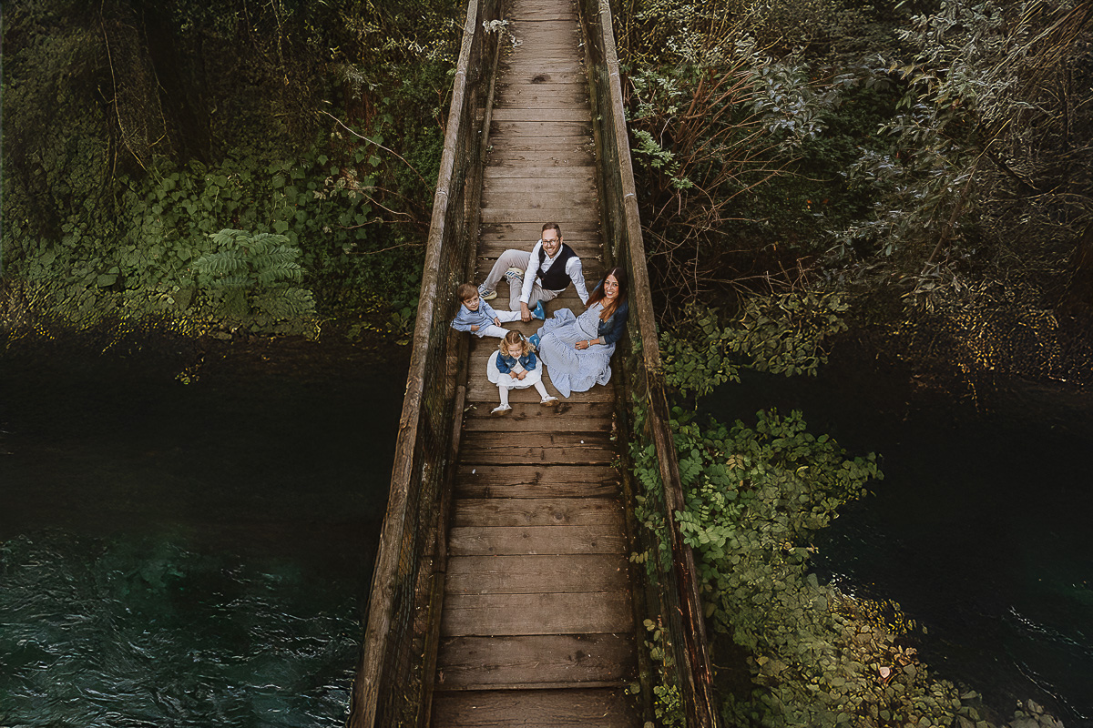 Fotografia di famiglia a Chieri, nel Giardino del Tessile. La famiglia è seduta sul ponte di legno sopra il Rio Tepice. Foto aerea dal drone.