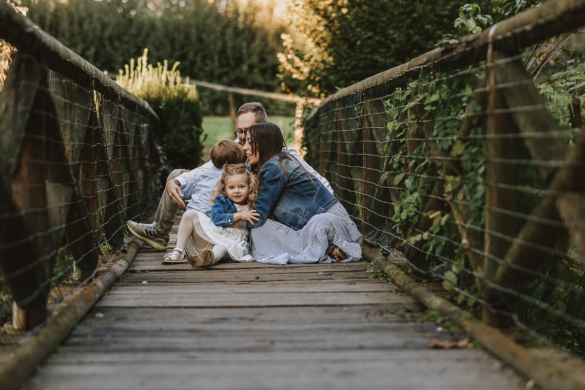 Fotografia di famiglia a Chieri, nel Giardino del Tessile. La famiglia è seduta sul ponte di legno sopra il Rio Tepice.