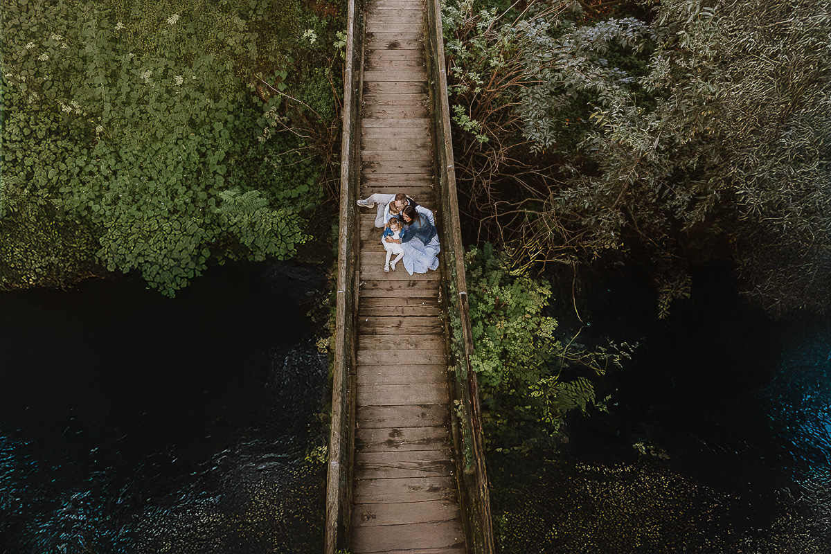 Fotografia di famiglia a Chieri, nel Giardino del Tessile. La famiglia è seduta sul ponte di legno sopra il Rio Tepice. Foto aerea dal drone.
