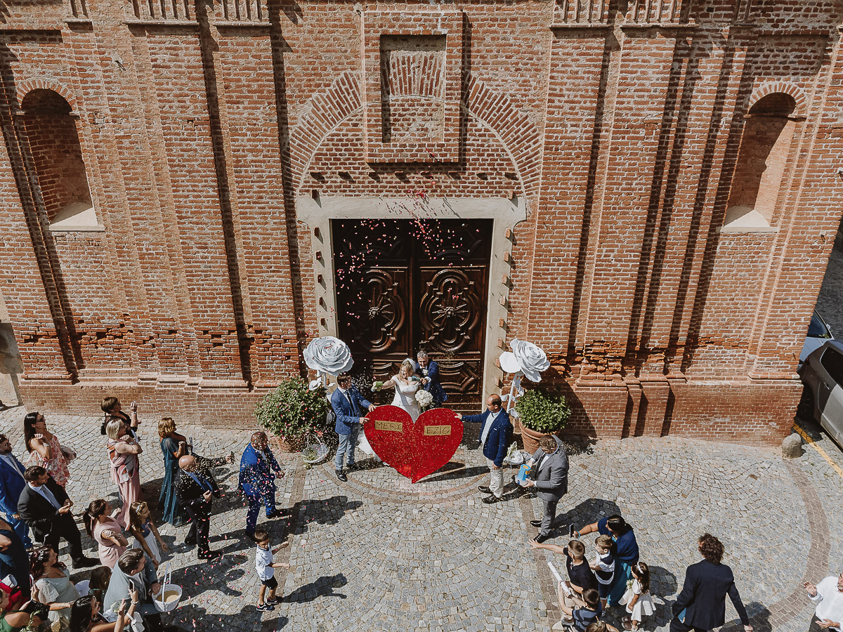 Fotografo Matrimonio in Piemonte. Cerimonia nella chiesa di San Giovanni Battista di Moriondo Torinese. Uscita degli sposi. Gli amici mettono un grande cuore davanti a loro. Foto aerea dal drone.