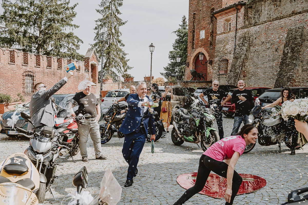 Fotografo Matrimonio in Piemonte. Cerimonia nella chiesa di San Giovanni Battista di Moriondo Torinese. Sposo corre sparando con un fucile sparabolle in mezzo alle moto.
