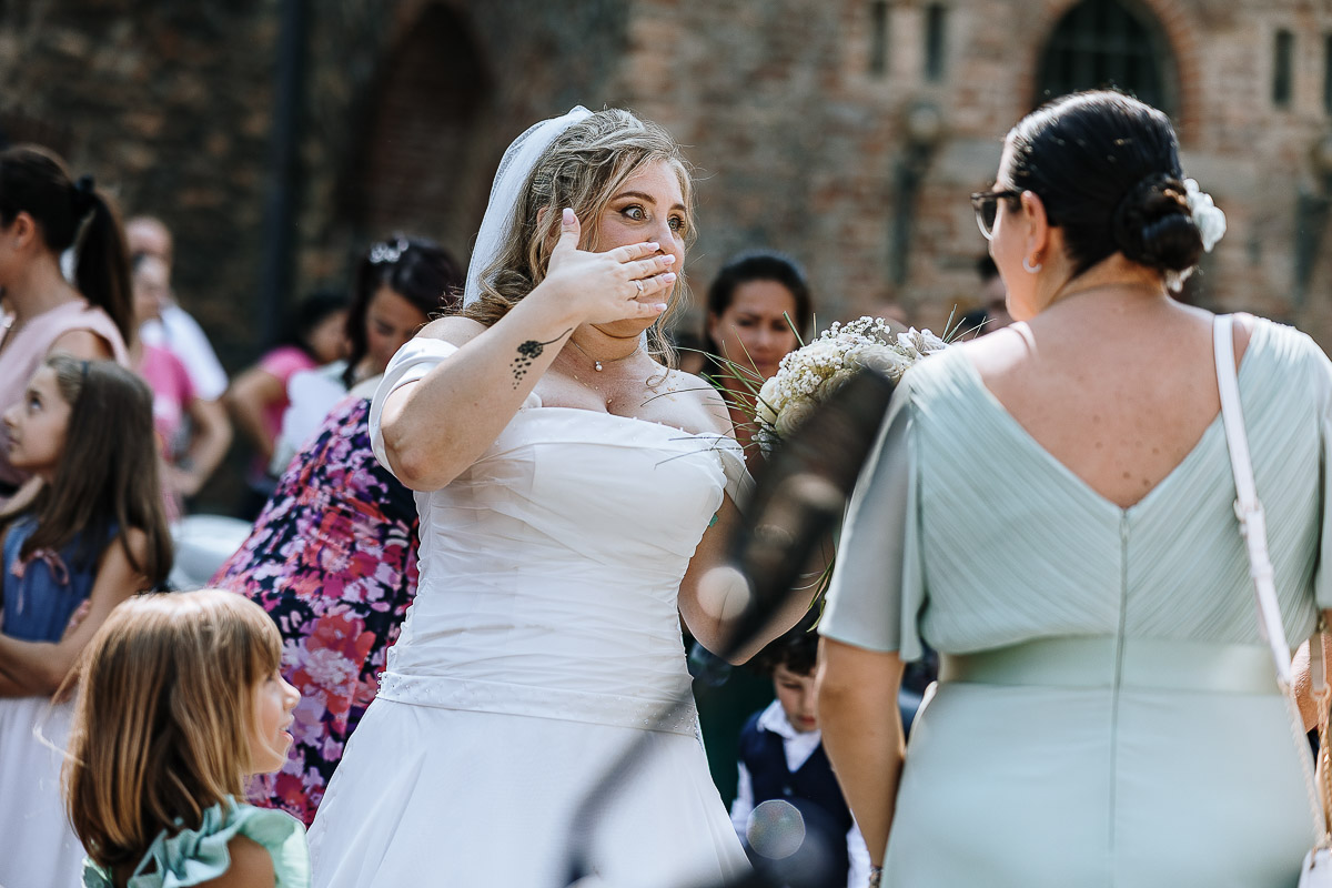Fotografo Matrimonio in Piemonte. Cerimonia nella chiesa di San Giovanni Battista di Moriondo Torinese. All'uscita gli amici motociclisti hanno creato un cuore con le moto e acceso dei fumi colorati rossi e verdi. Sposa manda baci.