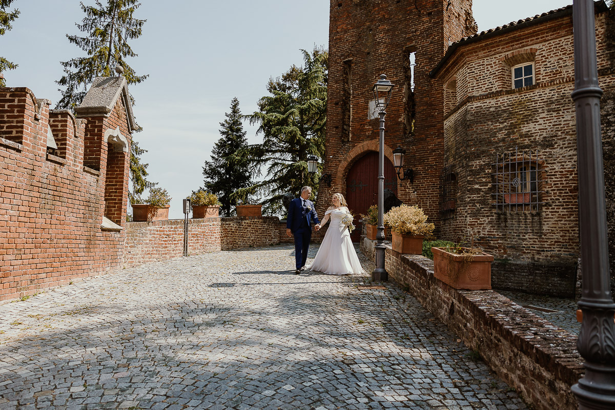Fotografo Matrimonio in Piemonte. Ritratti di coppia degli sposi davanti al castello di Moriondo Torinese. Gli sposi camminano.