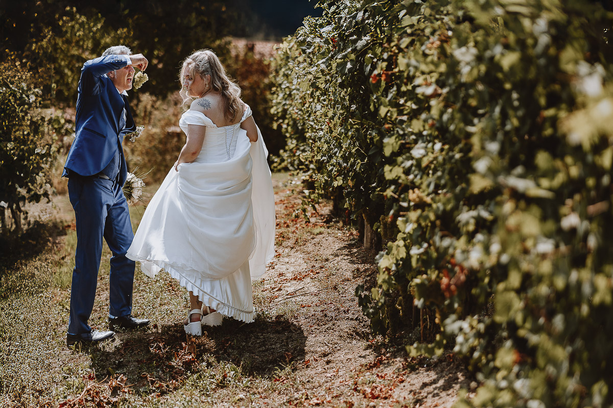 Fotografo Matrimonio in Piemonte. Ritratti di coppia degli sposi nel vigneto di famiglia a Moncucco Torinese. lo sposo mangia un grappolo d'uva.