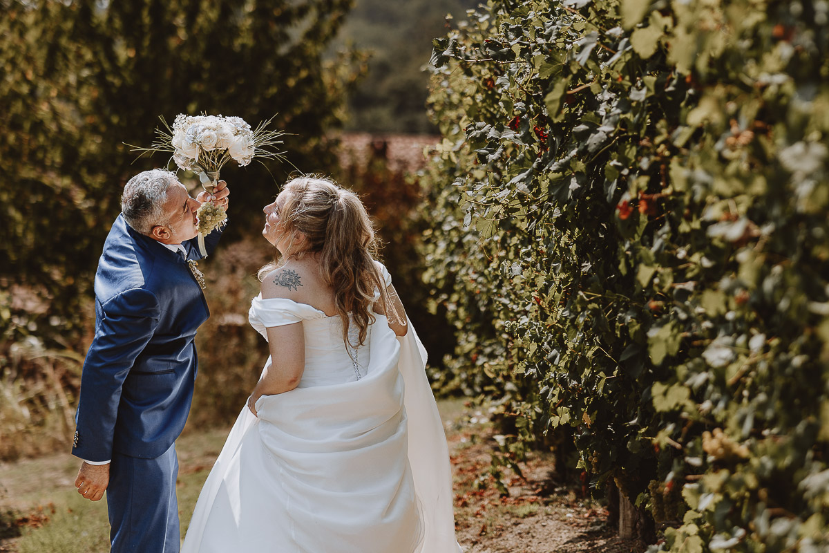 Fotografo Matrimonio in Piemonte. Ritratti di coppia degli sposi nel vigneto di famiglia a Moncucco Torinese. lo sposo mangia un grappolo d'uva.