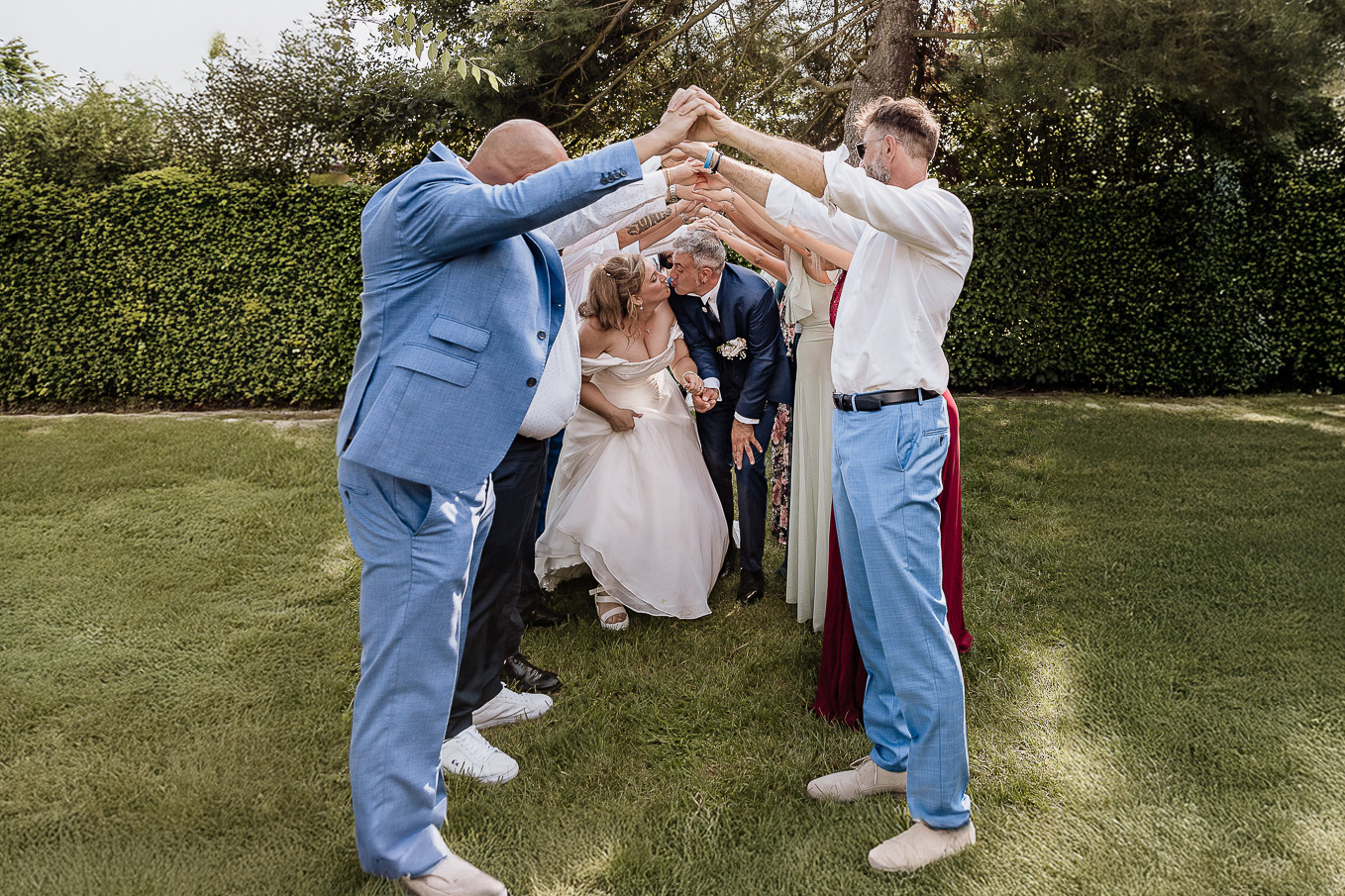Fotografo Matrimonio in Piemonte. Ricevimento all'agriturismo Greppi di Crescentino (VC). Aperitivo. Sposi passano sotto il ponte di mani fatti dagli amici.