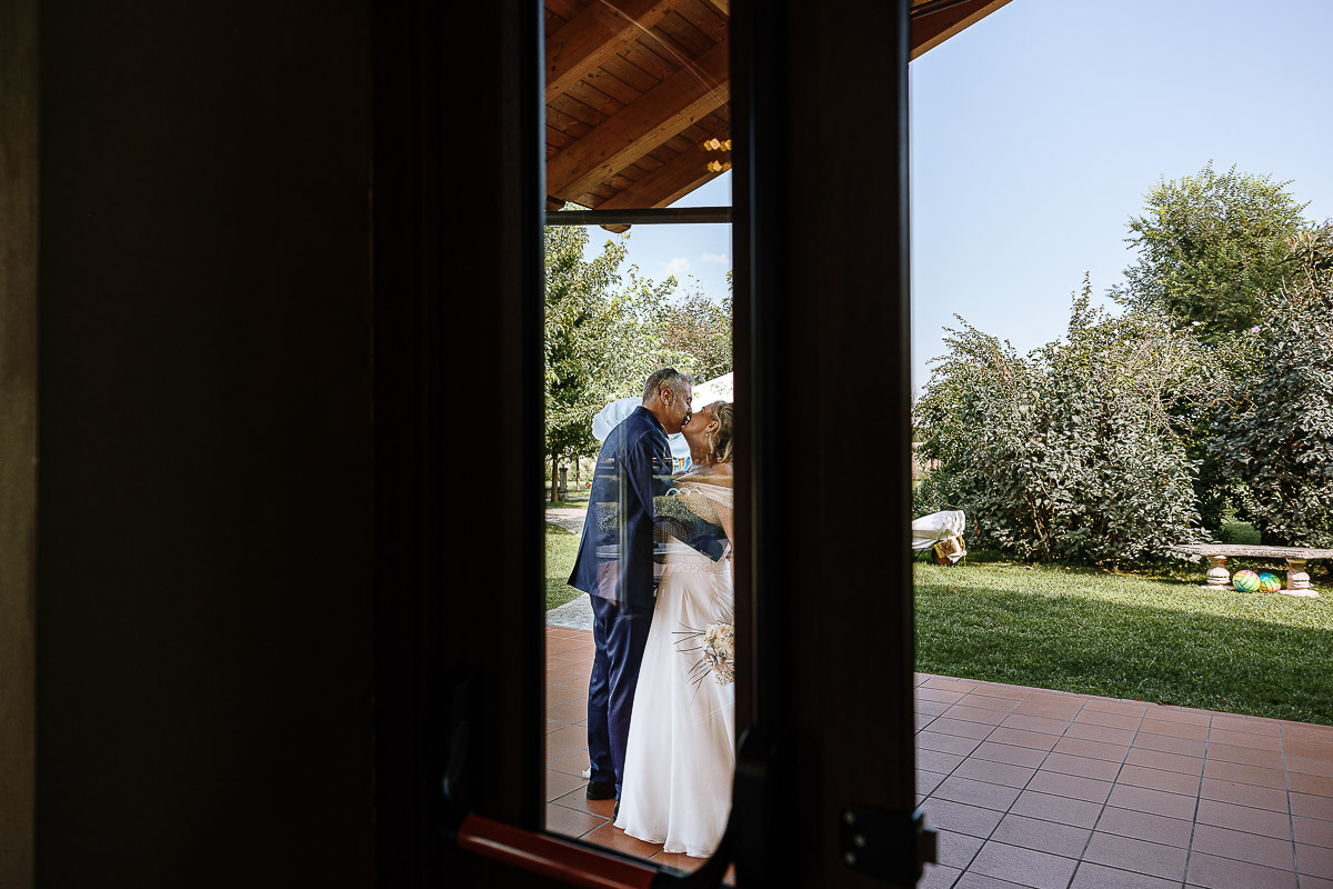 Fotografo Matrimonio in Piemonte. Ricevimento all'agriturismo Greppi di Crescentino (VC). Aperitivo. Sposi si baciano prima di entrare in sala.