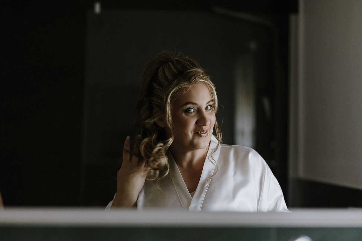 Fotografo Matrimonio in Piemonte. Preparazione a Moncucco Torinese. Sposa riflessa nello specchio del bagno.