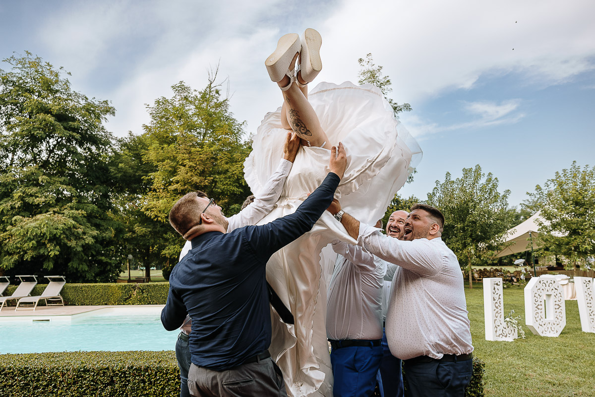Fotografo Matrimonio in Piemonte. Ricevimento all'agriturismo Greppi di Crescentino (VC). Pranzo nuziale. Amici fanno volare la sposa.