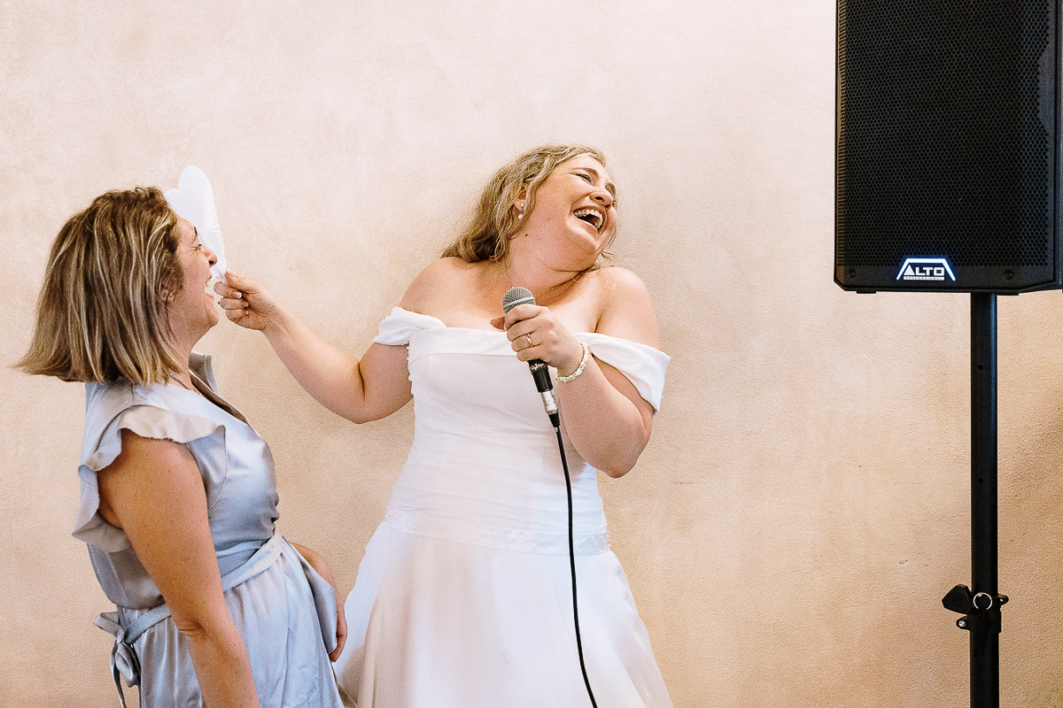 Fotografo Matrimonio in Piemonte. Ricevimento all'agriturismo Greppi di Crescentino (VC). Pranzo nuziale. Sposa e amica cantano.