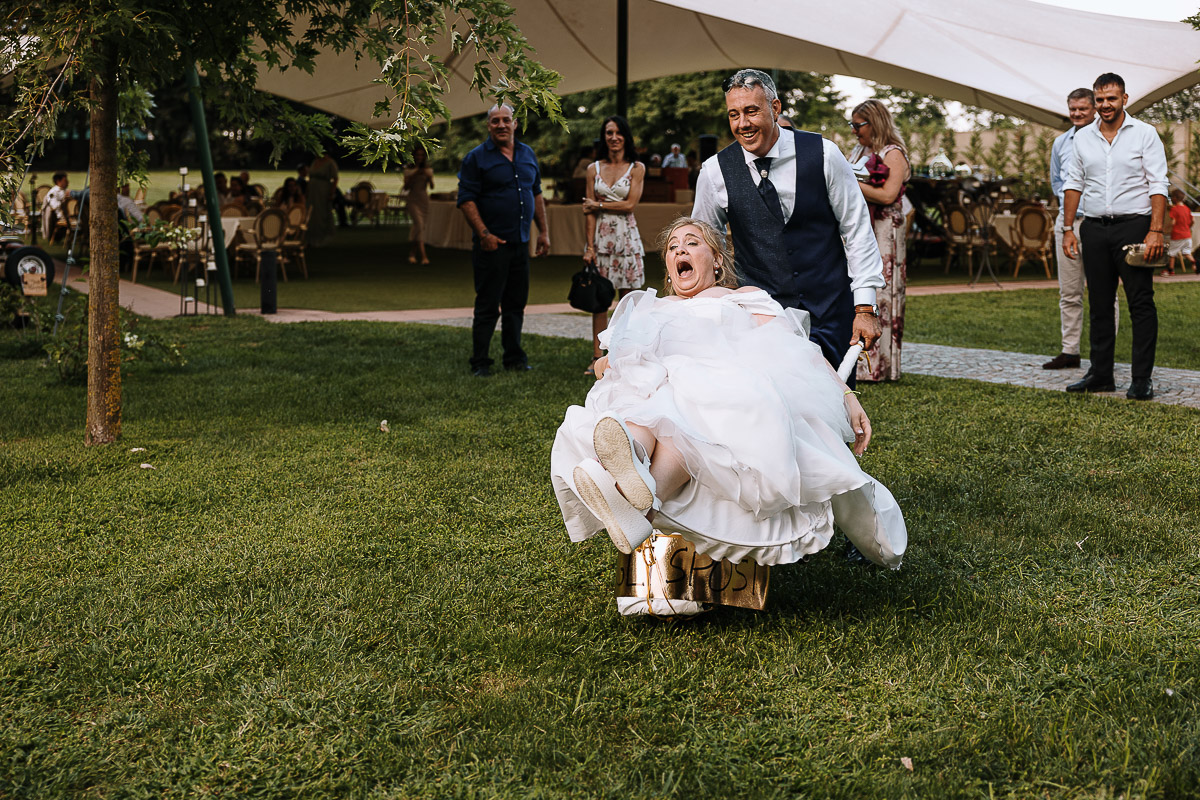 Fotografo Matrimonio in Piemonte. Ricevimento all'agriturismo Greppi di Crescentino (VC). Ricevimento. Taglio torta. Lo sposo porta la sposa su di una carriola.