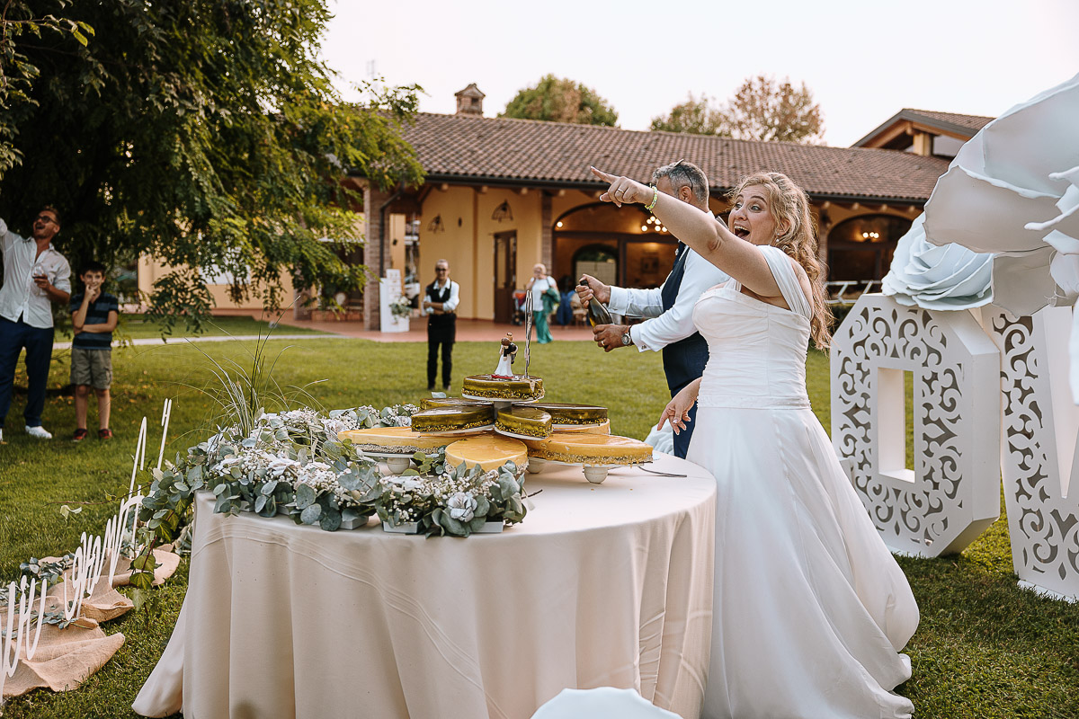 Fotografo Matrimonio in Piemonte. Ricevimento all'agriturismo Greppi di Crescentino (VC). Ricevimento. Taglio torta. Lo sposo apre la bottiglia di spumante