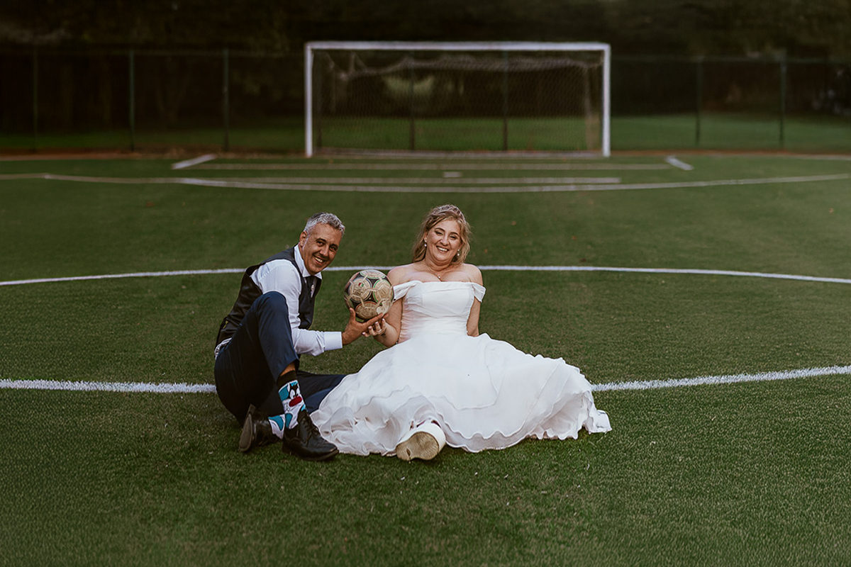 Fotografo Matrimonio in Piemonte. Ricevimento all'agriturismo Greppi di Crescentino (VC). Ricevimento. Ritratti degli sposi al campo di calcio. Sposi seduti sul terreno di gioco. lo sposo ha in mano il pallone.