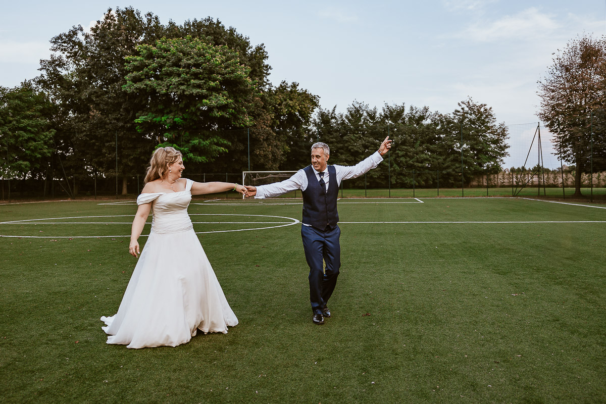 Fotografo Matrimonio in Piemonte. Ricevimento all'agriturismo Greppi di Crescentino (VC). Ricevimento. Ritratti degli sposi al campo di calcio. Lo sposo gira intorno alla sposa.