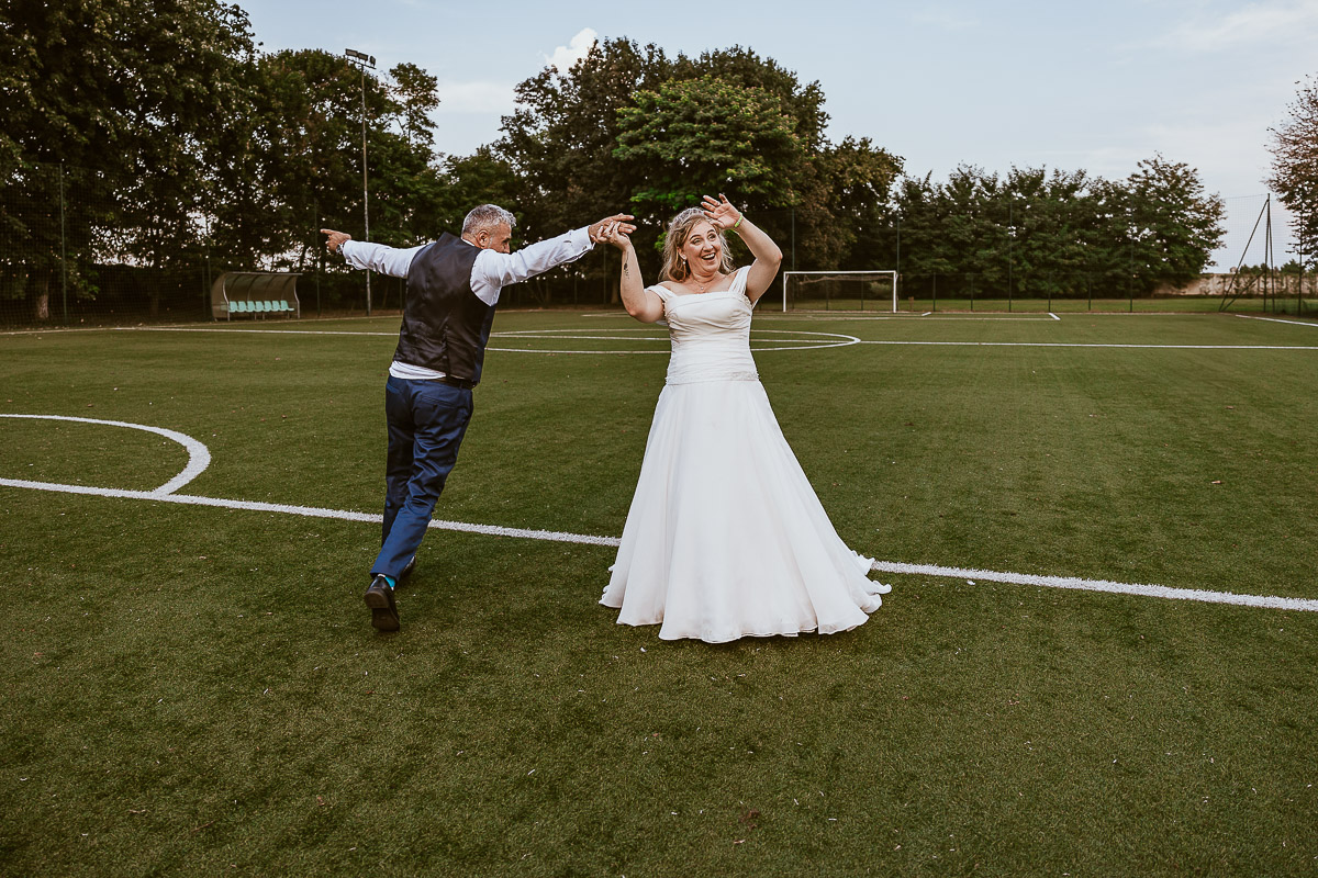 Fotografo Matrimonio in Piemonte. Ricevimento all'agriturismo Greppi di Crescentino (VC). Ricevimento. Ritratti degli sposi al campo di calcio. Lo sposo gira intorno alla sposa.